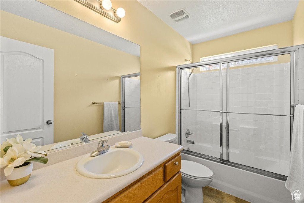 Bathroom featuring toilet, vanity, and combined bath / shower with glass door