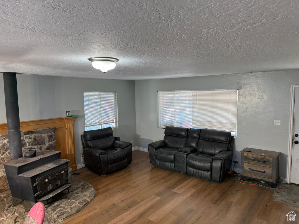 Living room with wood finished floors, a textured ceiling, and a wood stove