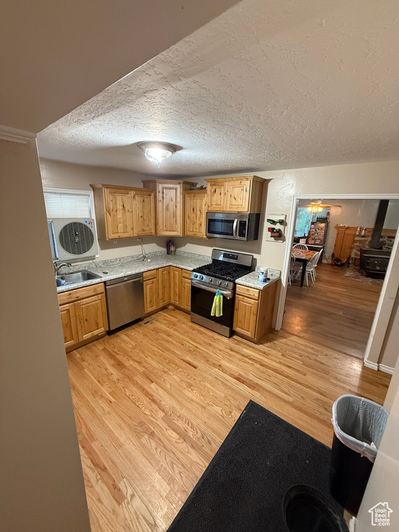 Kitchen featuring stainless steel appliances, a sink, light wood-style floors, light countertops, and a textured ceiling