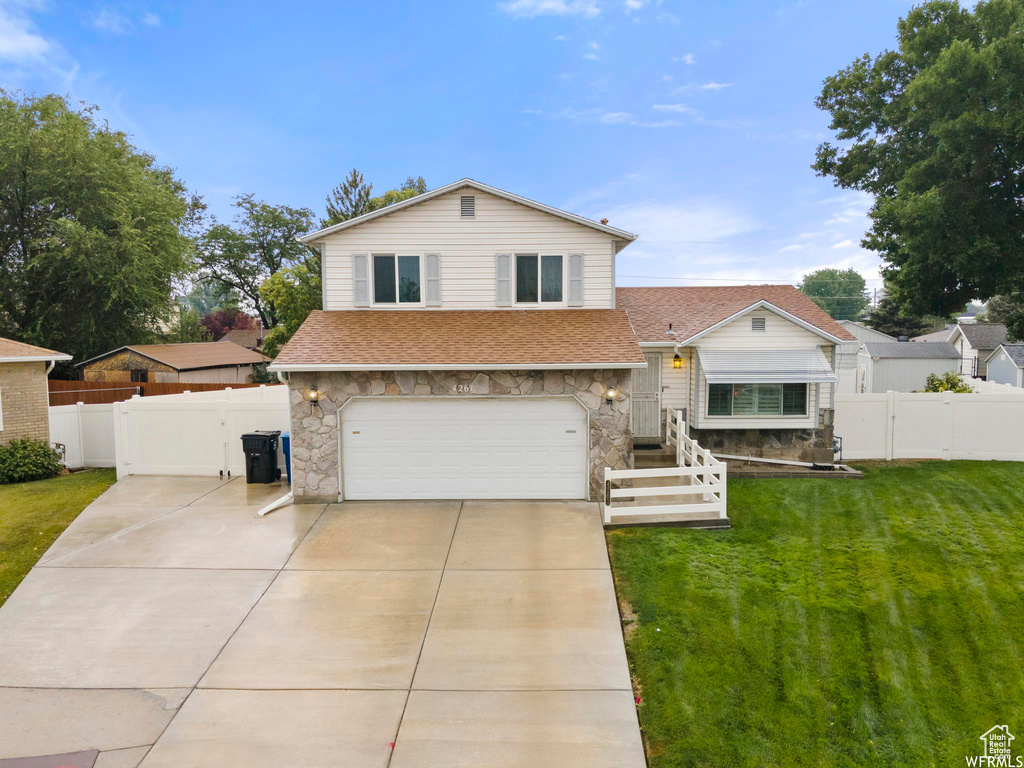 Split level home with stone siding, a gate, and roof with shingles