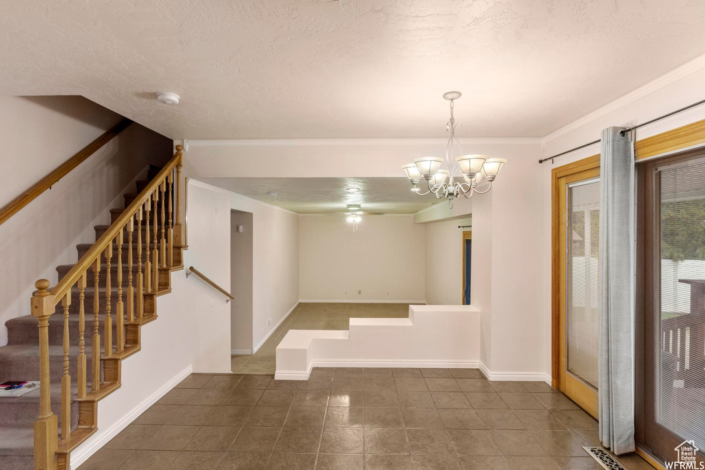 Entryway featuring stairway, dark tile patterned floors, a chandelier, crown molding, and baseboards