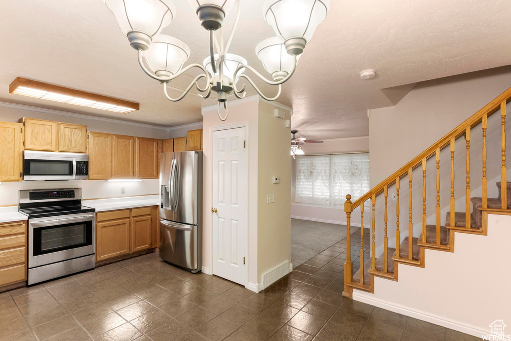 Kitchen with appliances with stainless steel finishes, light countertops, baseboards, a chandelier, and dark tile patterned floors