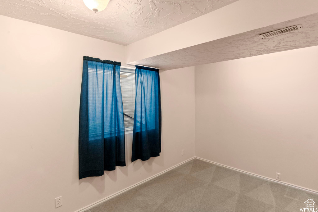 Unfurnished room featuring baseboards, carpet, and a textured ceiling