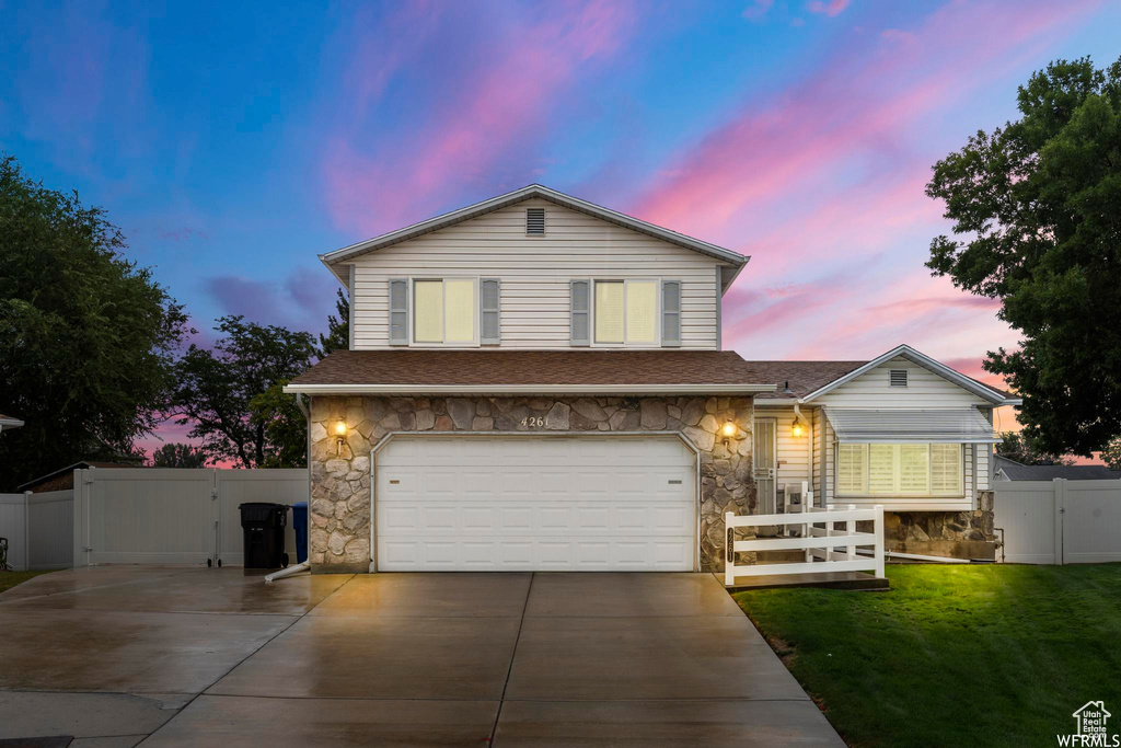View of front of property with a gate, stone siding, concrete driveway, and a garage