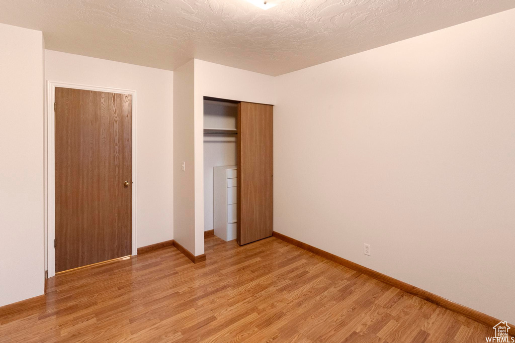 Unfurnished bedroom with light wood finished floors, a closet, and baseboards