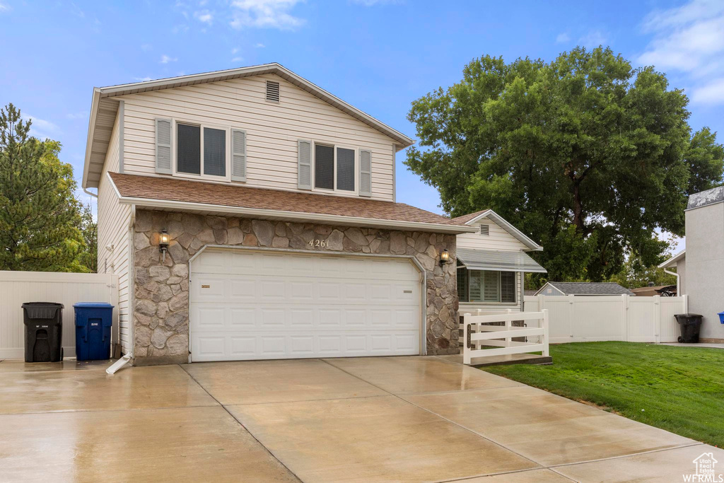 View of front of home featuring stone siding, driveway, an attached garage, and roof with shingles