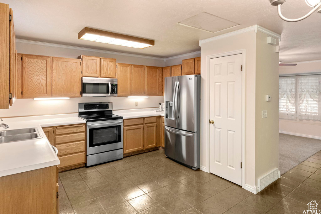 Kitchen featuring stainless steel appliances, a sink, ornamental molding, light countertops, and light brown cabinets