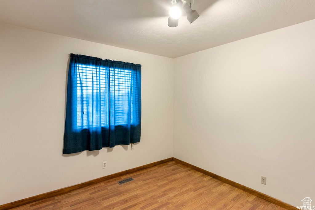 Empty room featuring light wood-type flooring, baseboards, and a ceiling fan