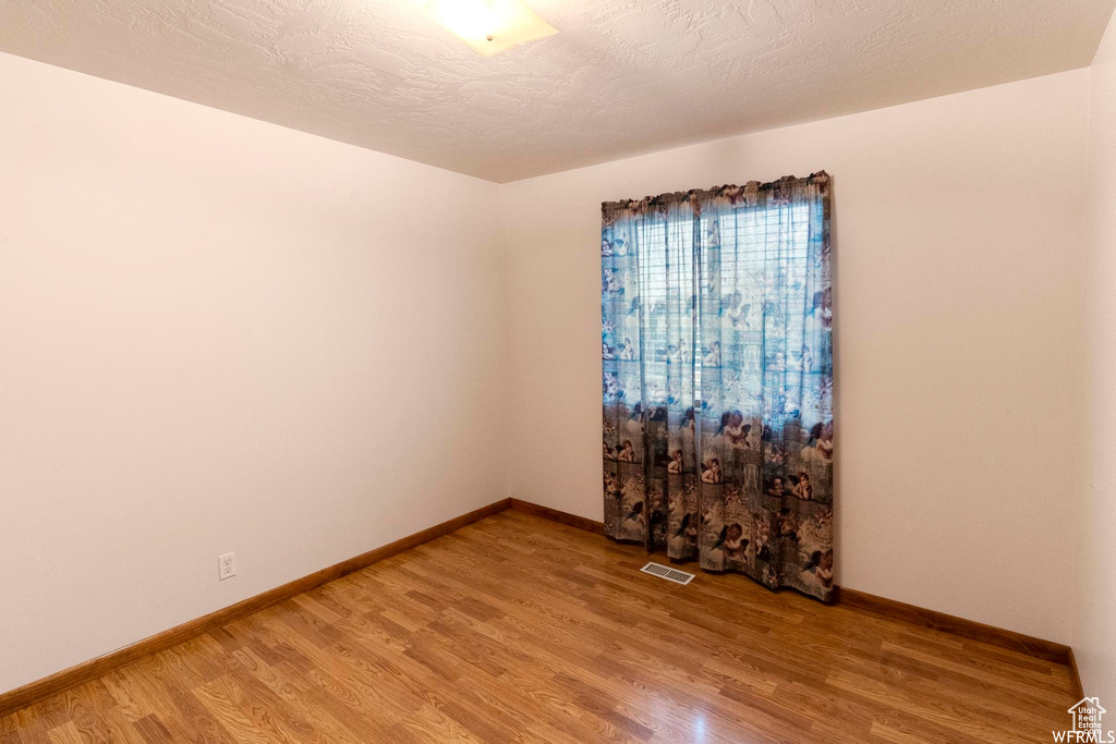 Spare room featuring light wood-style flooring and baseboards