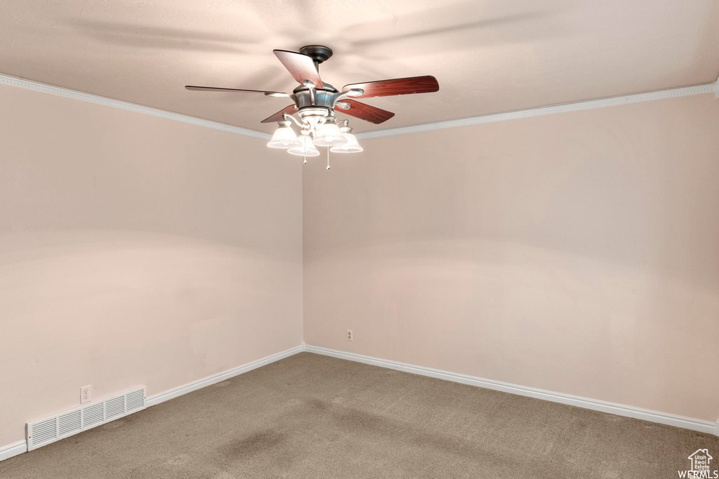 Carpeted empty room featuring ceiling fan, ornamental molding, and baseboards