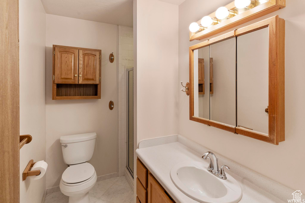 Full bath featuring toilet, vanity, baseboards, a shower with door, and tile patterned flooring