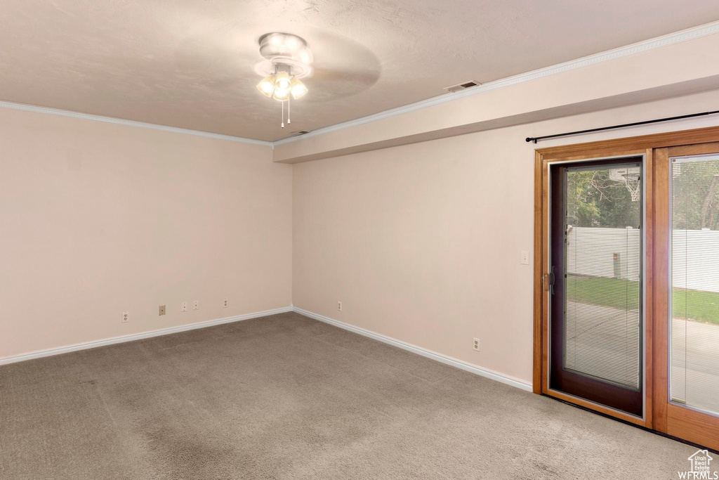 Empty room featuring crown molding, carpet, a ceiling fan, and baseboards