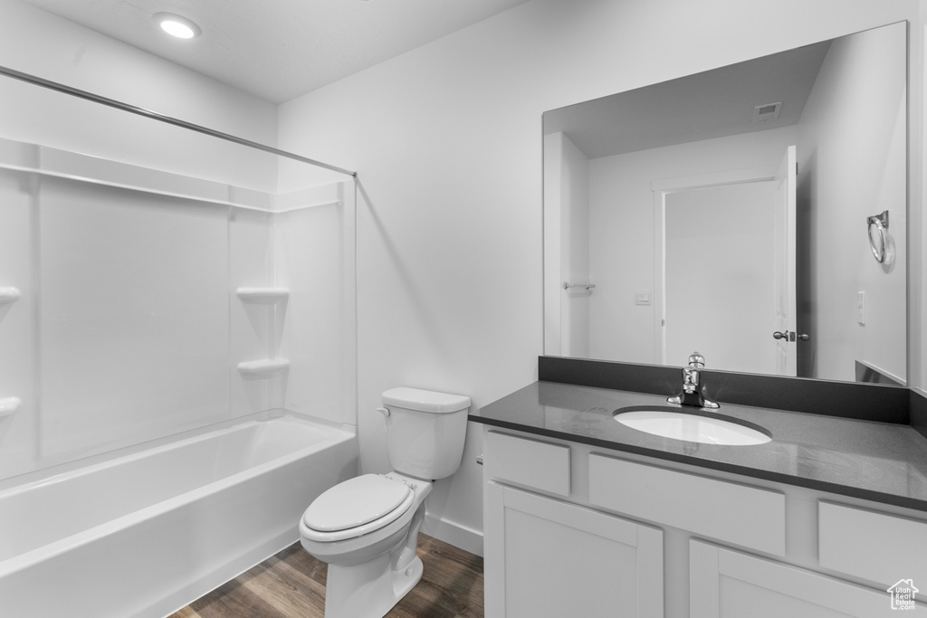 Bathroom with vanity, toilet, wood finished floors, shower / bathtub combination, and baseboards