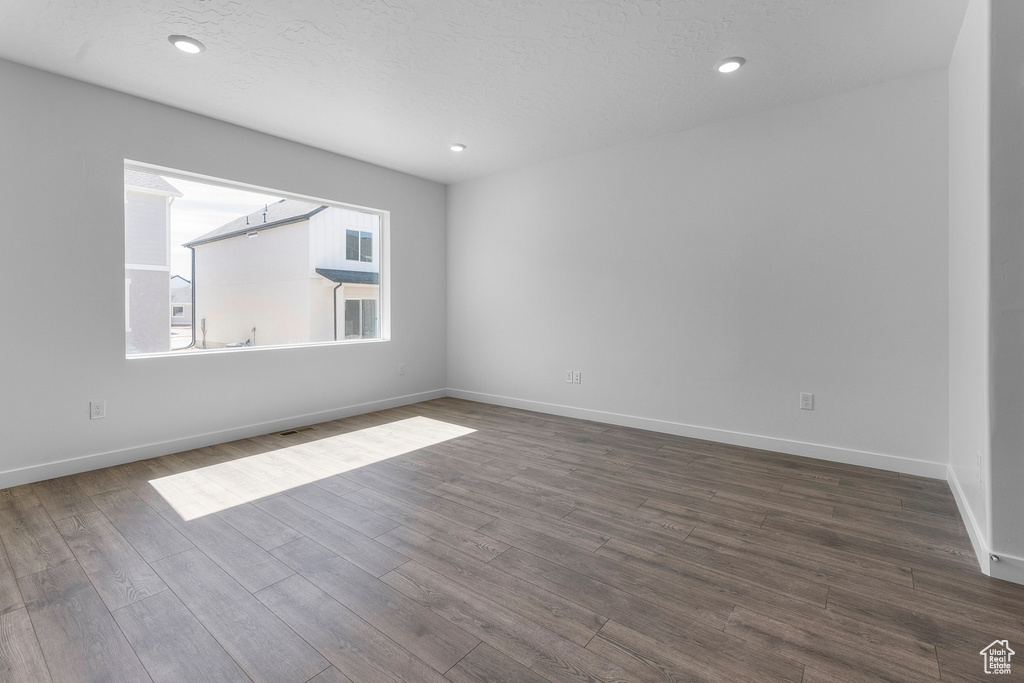 Empty room featuring dark wood-type flooring, baseboards, and recessed lighting