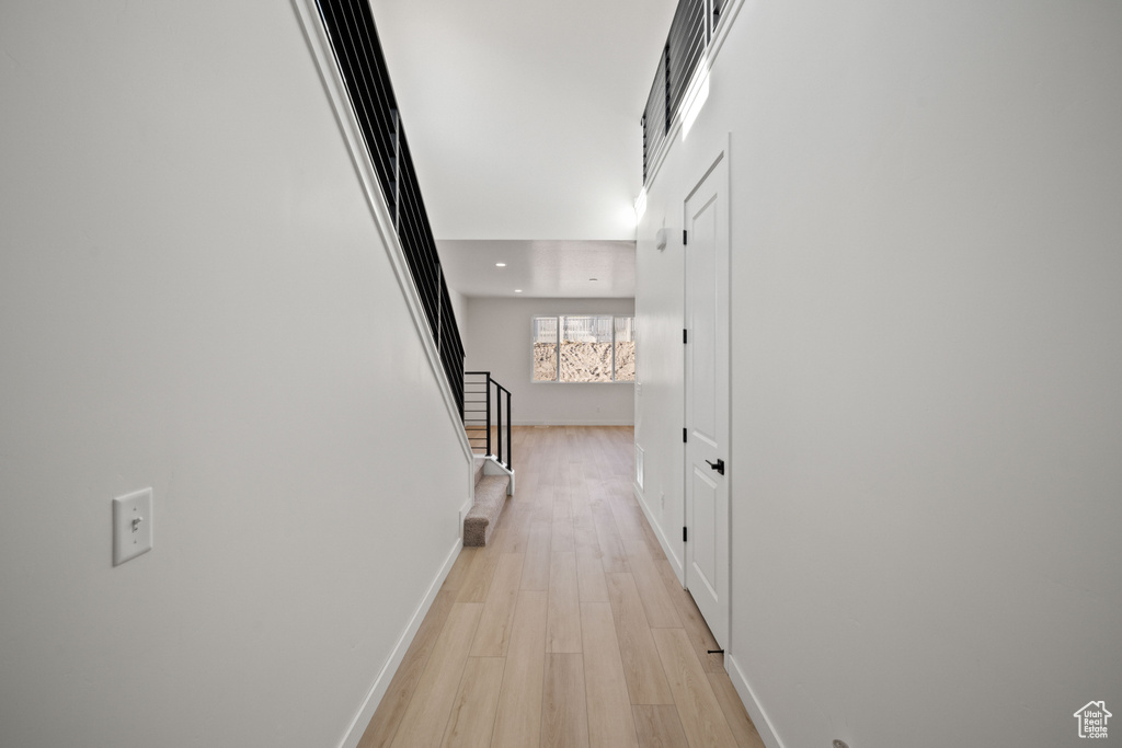 Corridor with light wood-style flooring, stairs, baseboards, and recessed lighting