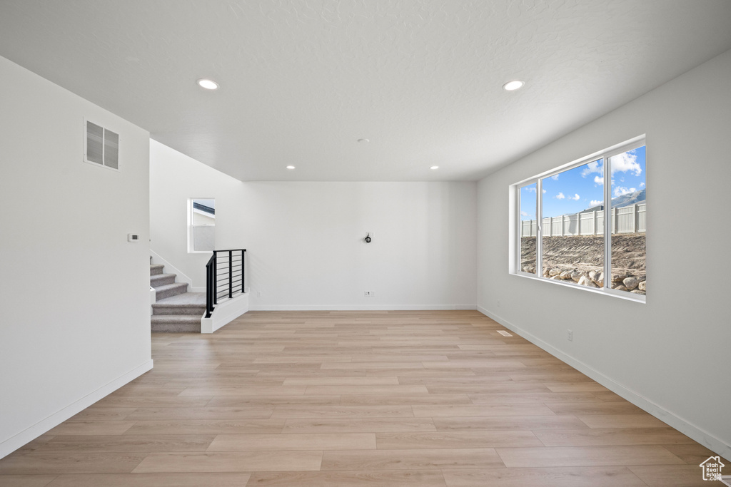 Unfurnished room featuring stairway, recessed lighting, light wood-style flooring, and baseboards