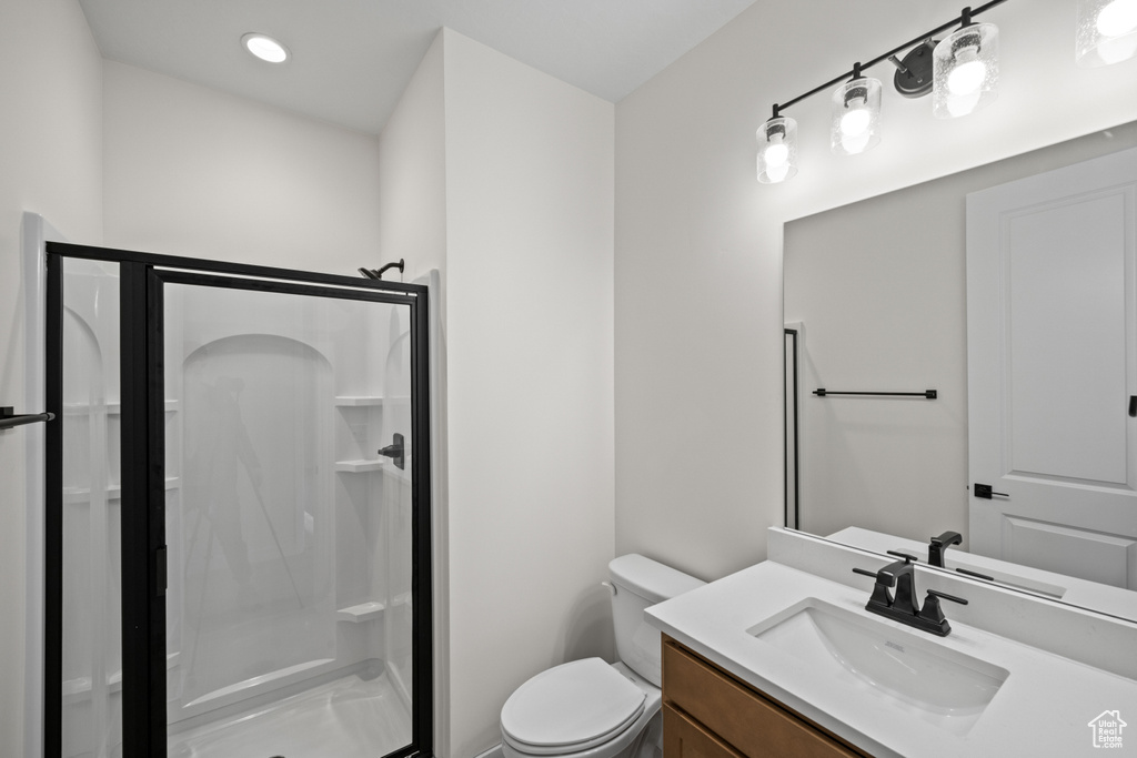 Bathroom featuring a stall shower, vanity, and toilet