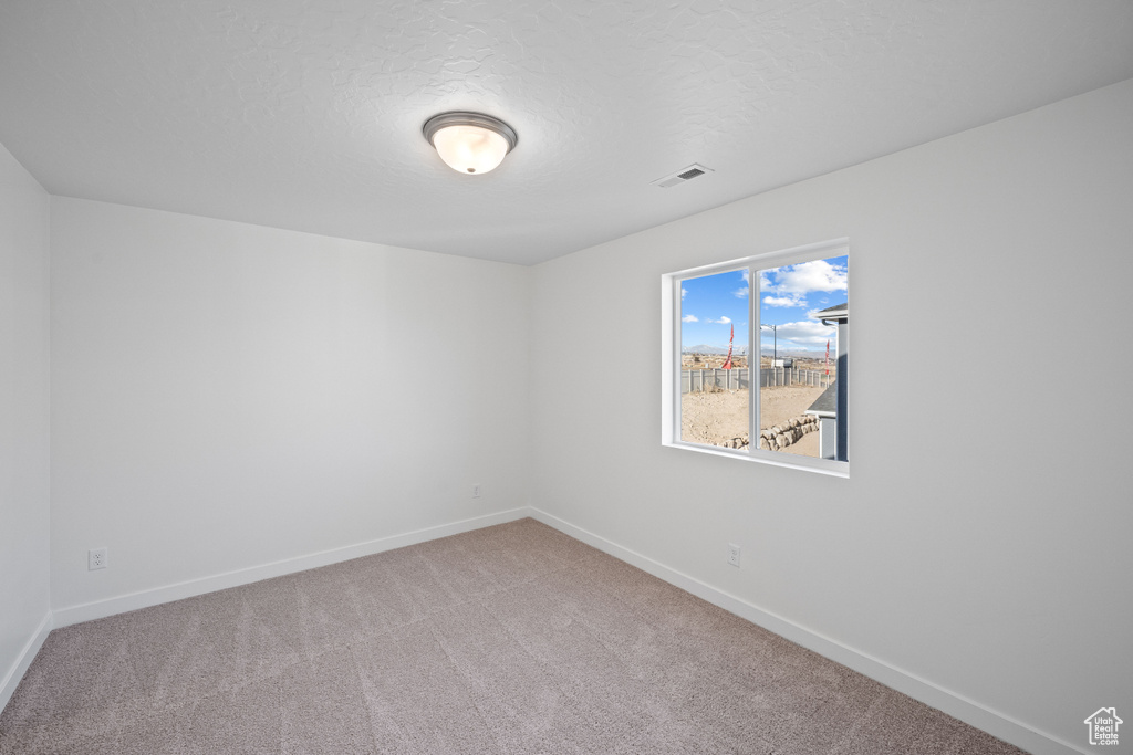 Carpeted empty room with baseboards and a textured ceiling