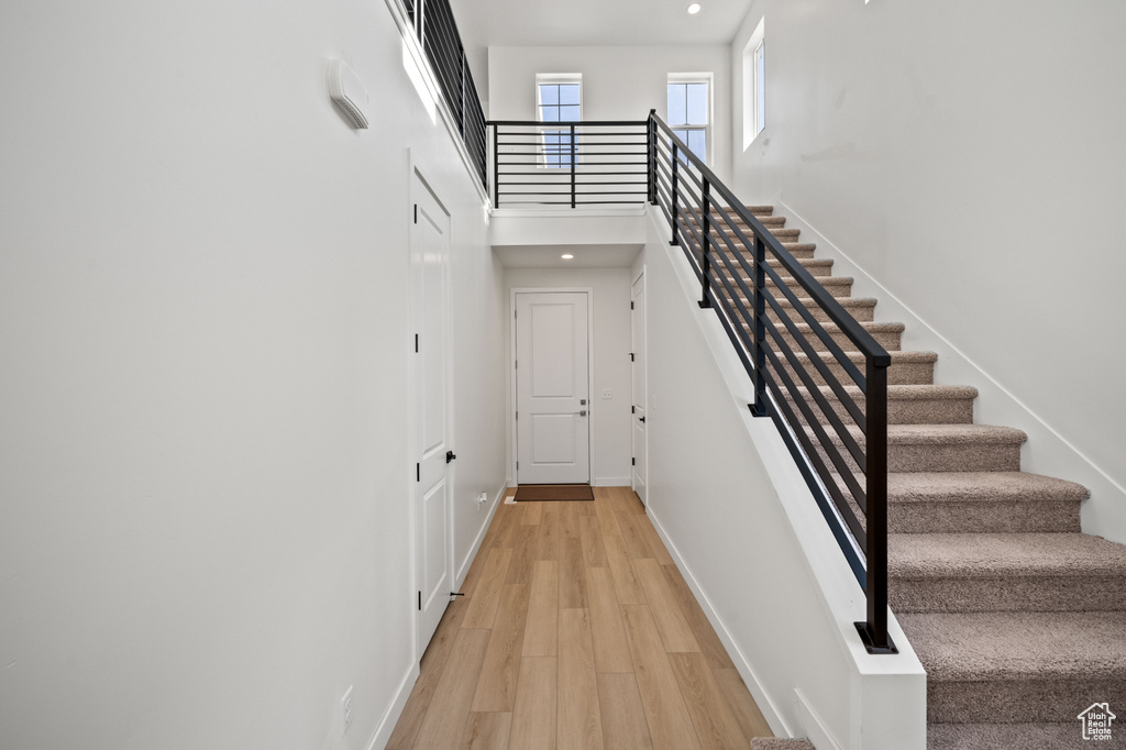 Staircase featuring wood finished floors, baseboards, a towering ceiling, and recessed lighting
