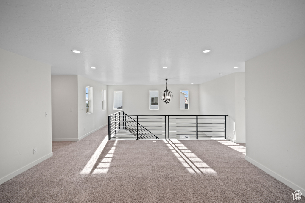 Empty room featuring carpet, baseboards, a chandelier, and recessed lighting