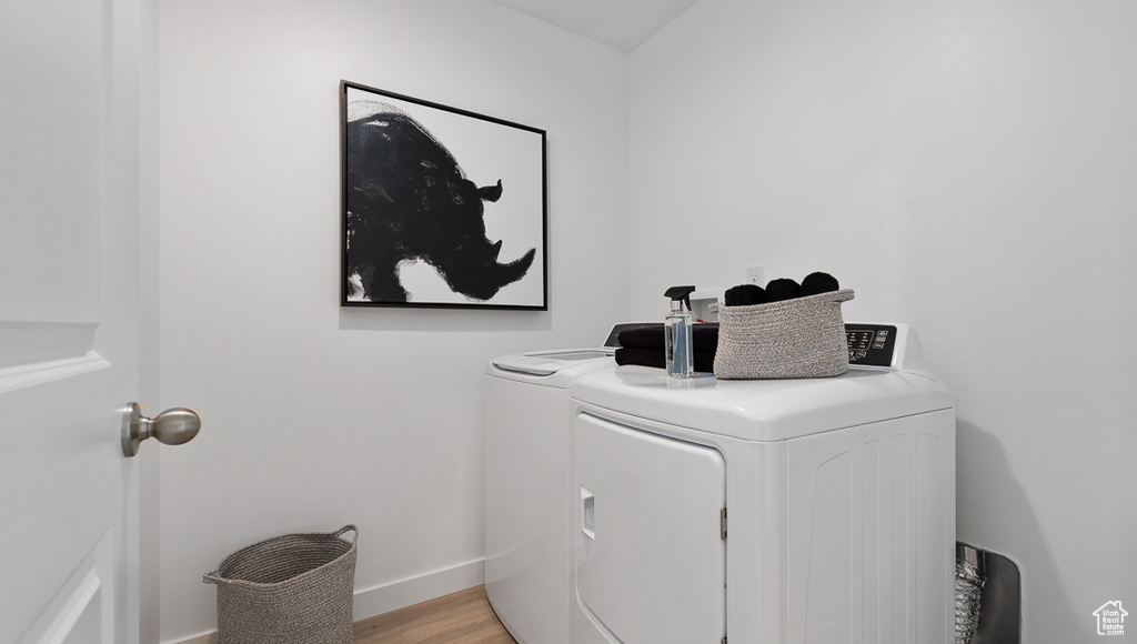 Laundry area featuring washer and clothes dryer, baseboards, and light wood-style floors