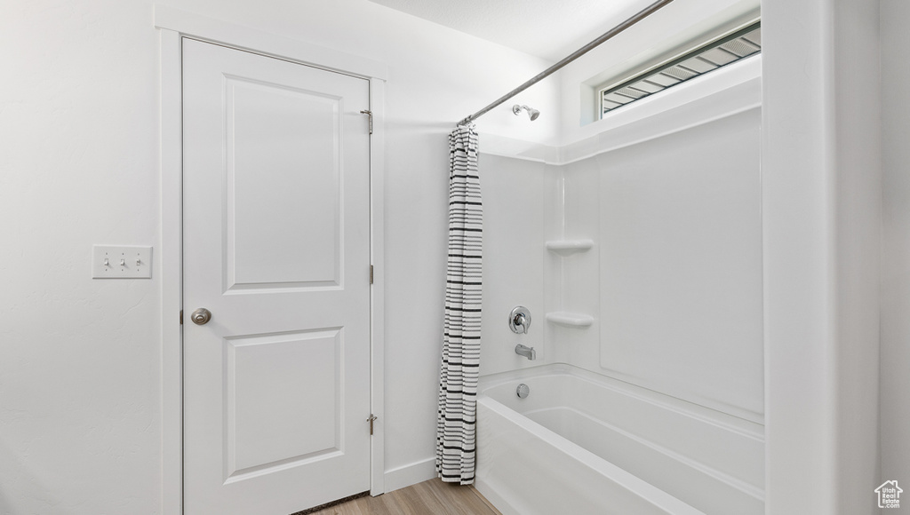 Bathroom with shower / bath combo, wood finished floors, and baseboards