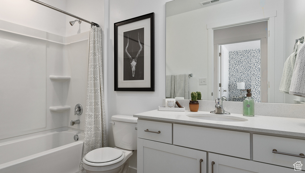 Full bath with vanity, shower / bath combo with shower curtain, and toilet