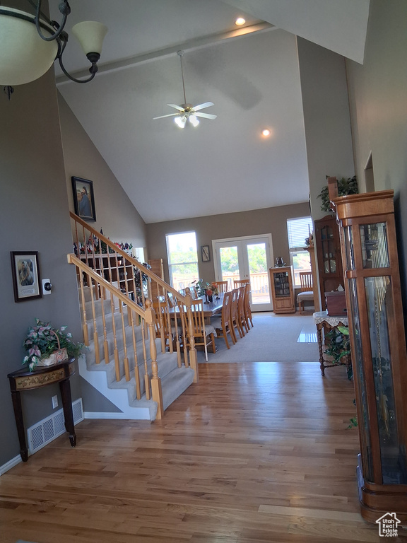 Staircase with high vaulted ceiling, wood finished floors, ceiling fan, recessed lighting, and baseboards