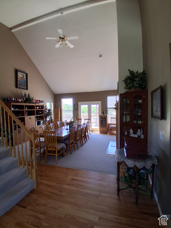 Dining area featuring wood finished floors, a ceiling fan, stairs, and high vaulted ceiling