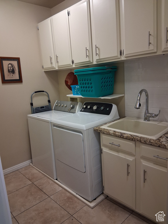 Washroom with independent washer and dryer, cabinet space, light tile patterned flooring, and baseboards