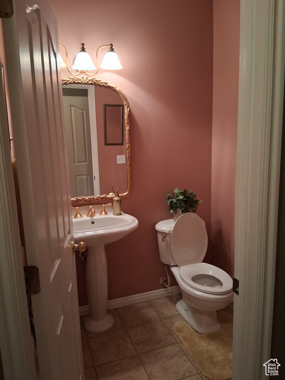Bathroom featuring toilet, tile patterned flooring, and baseboards