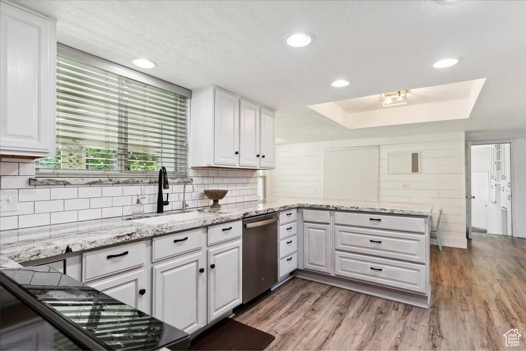 Kitchen featuring dishwasher, a sink, white cabinetry, a tray ceiling, and recessed lighting