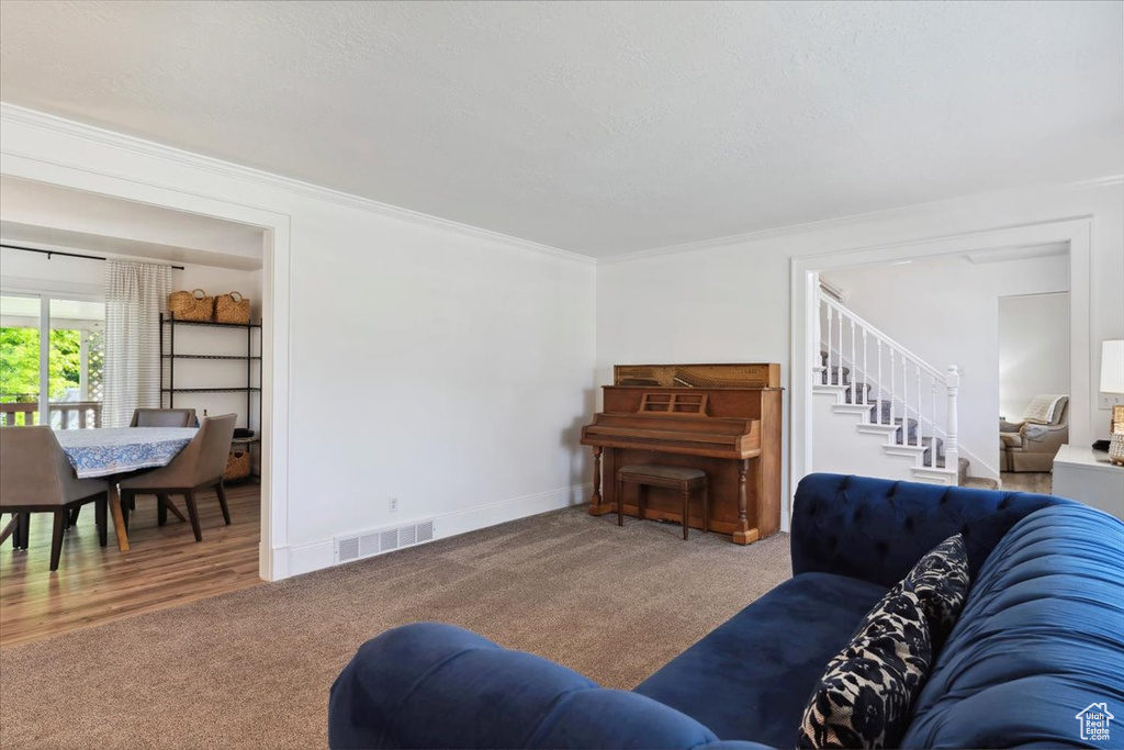 Living room with carpet, stairs, ornamental molding, and baseboards