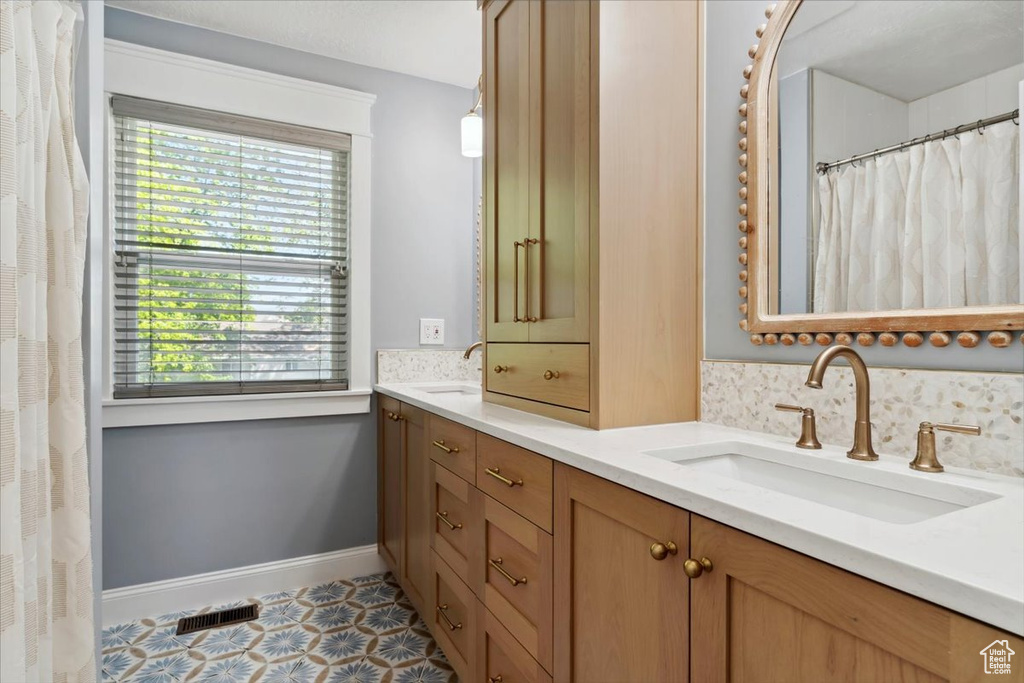 Full bathroom with double vanity and baseboards