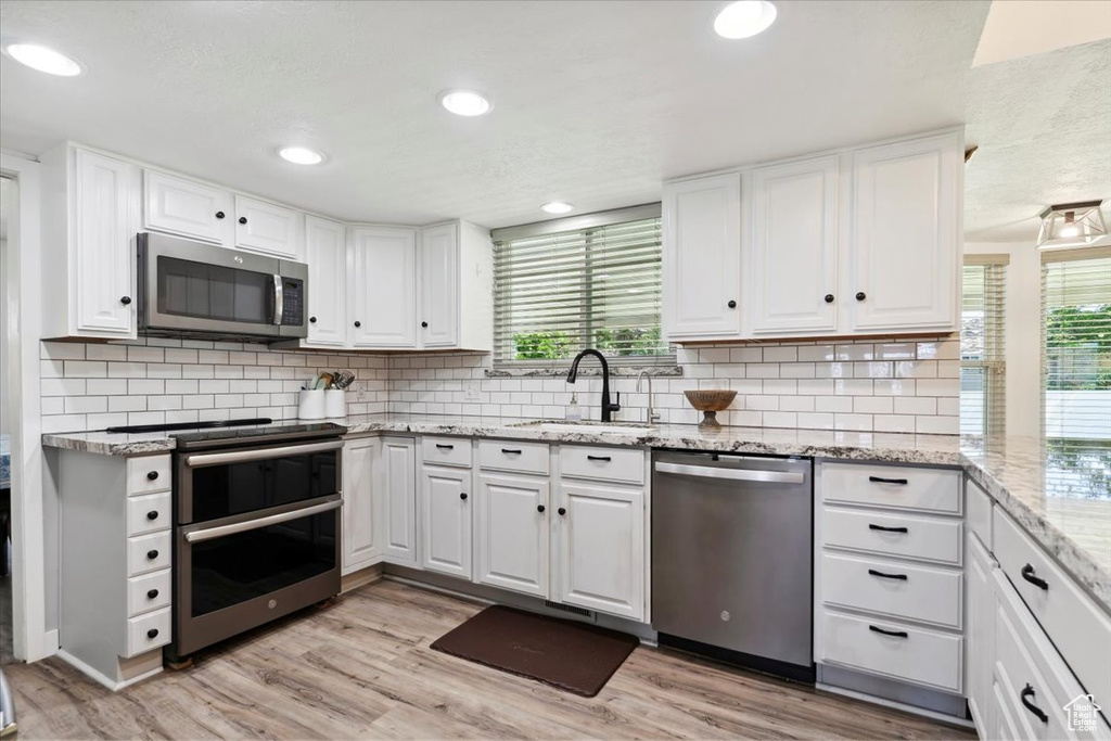 Kitchen with stainless steel appliances, healthy amount of natural light, white cabinetry, and recessed lighting