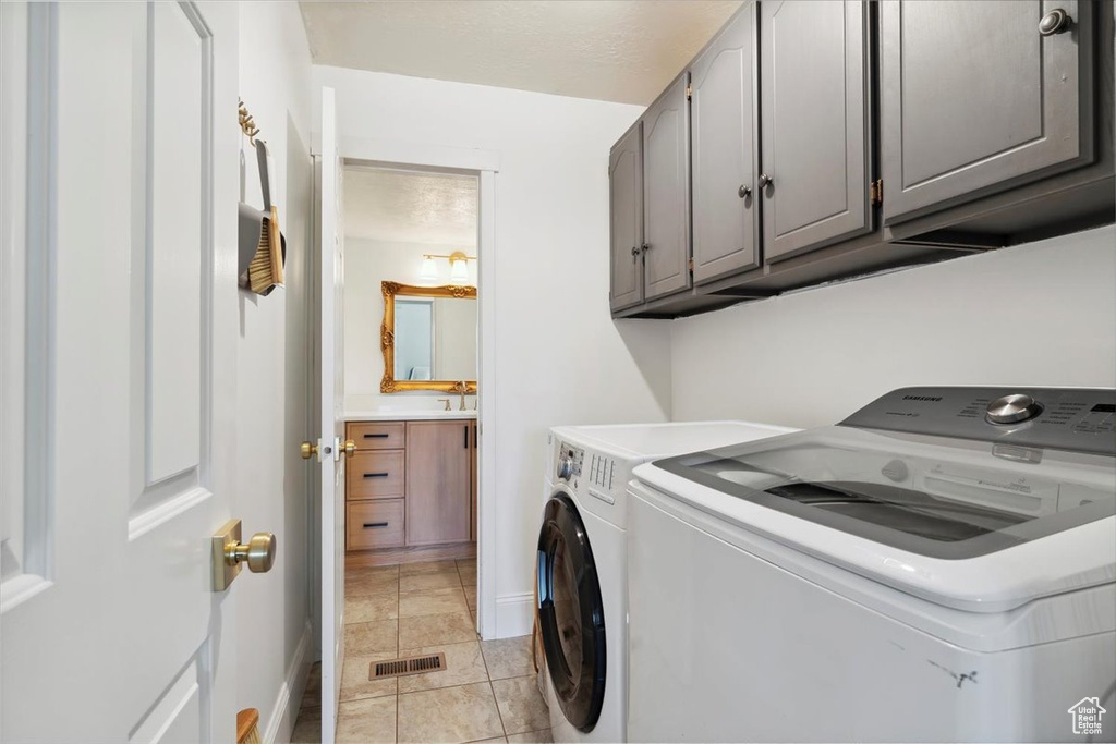 Laundry area featuring washing machine and clothes dryer, cabinet space, and baseboards