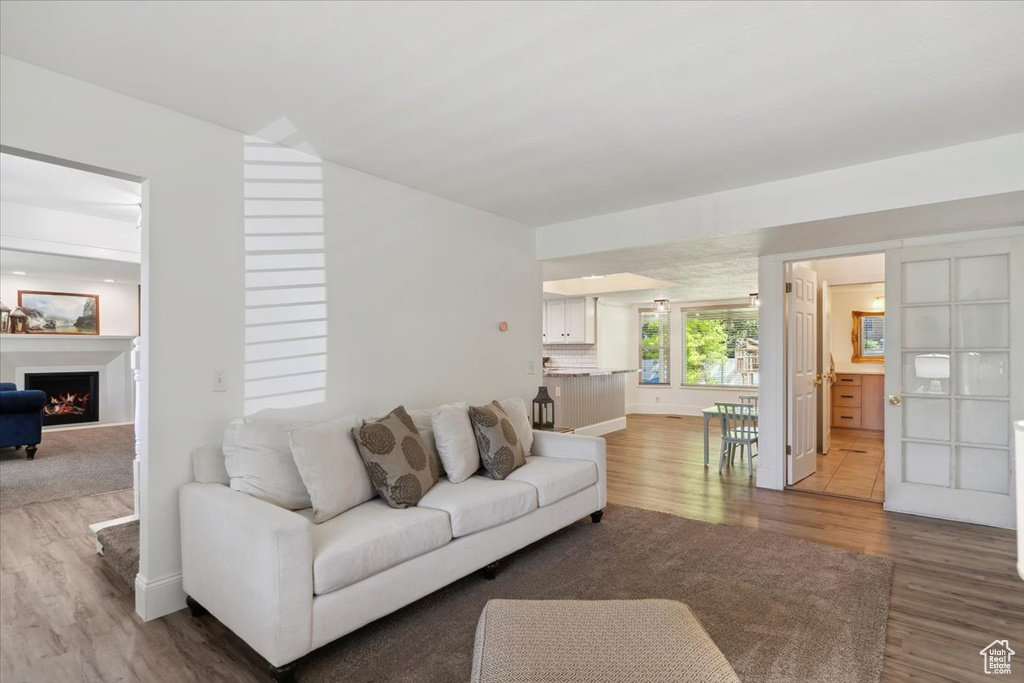 Living room with wood finished floors, a lit fireplace, and baseboards