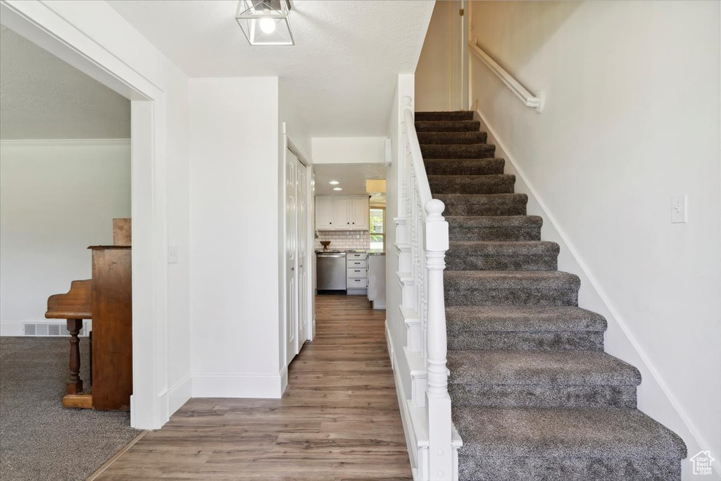 Staircase with wood finished floors and baseboards