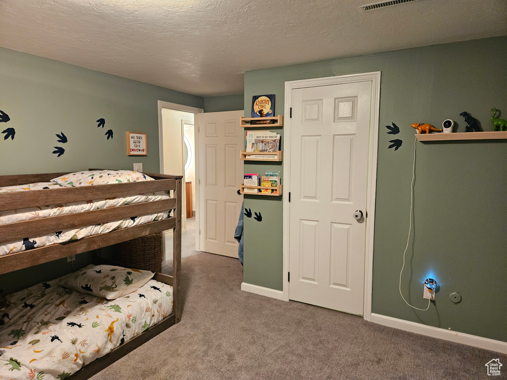 Carpeted bedroom featuring a textured ceiling and baseboards