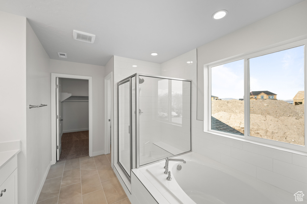 Full bathroom featuring a stall shower, a garden tub, a spacious closet, vanity, and recessed lighting