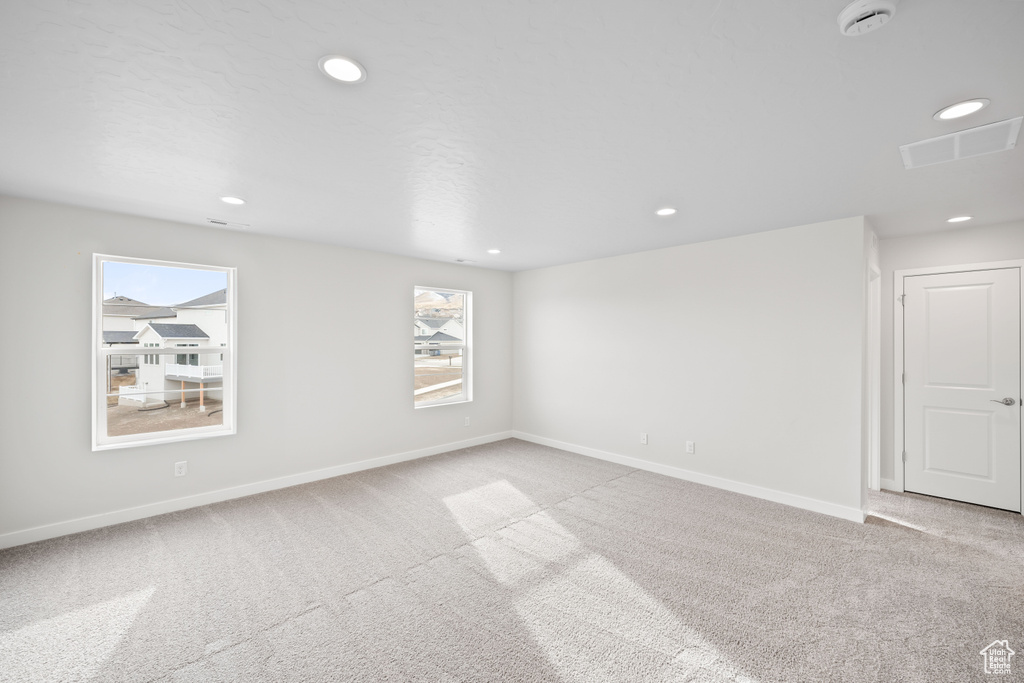 Carpeted empty room featuring baseboards, recessed lighting, and a smoke detector
