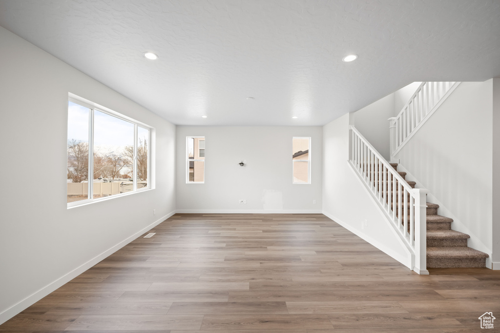 Unfurnished living room with stairway, recessed lighting, baseboards, and wood finished floors