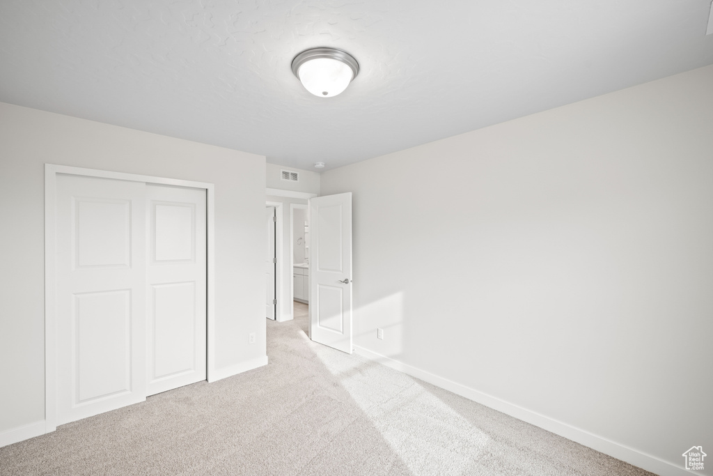 Unfurnished bedroom featuring carpet, baseboards, and a closet