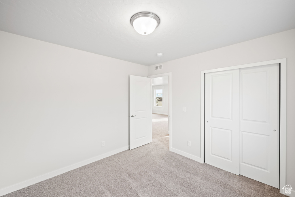 Unfurnished bedroom with carpet flooring, baseboards, and a closet