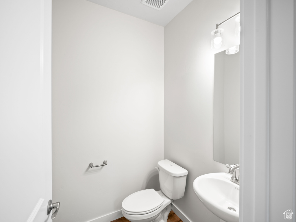 Bathroom with a sink, toilet, wood finished floors, and baseboards