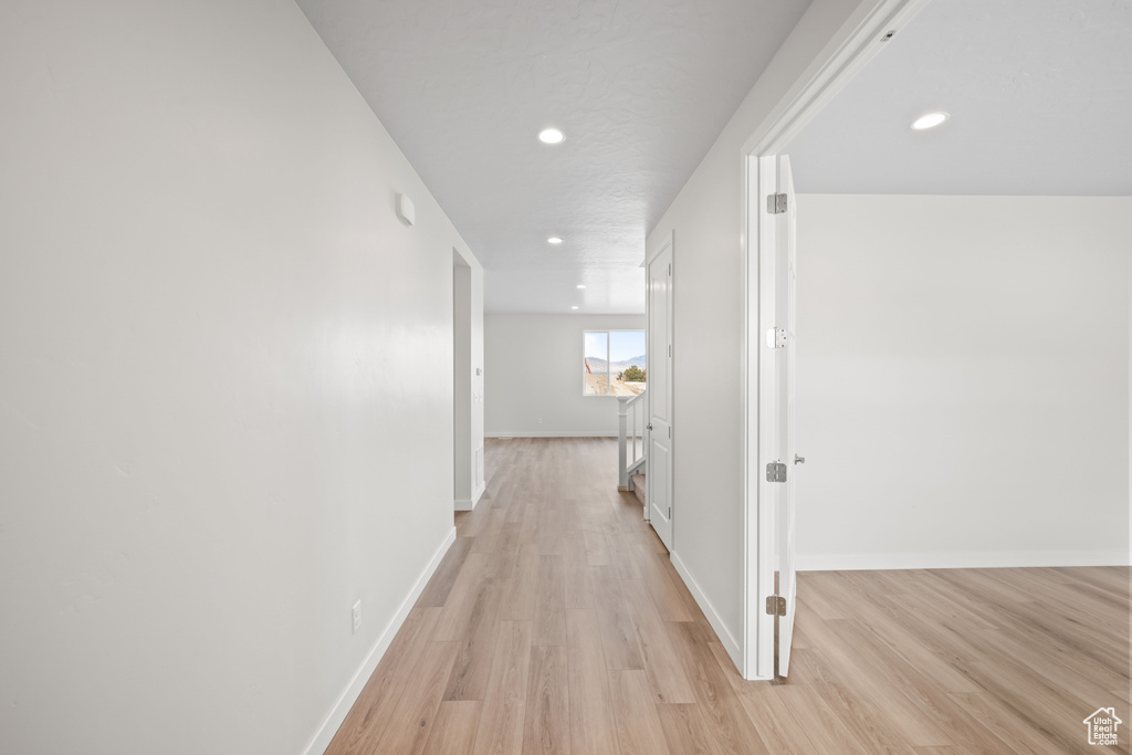Hall with recessed lighting, light wood-style floors, and baseboards