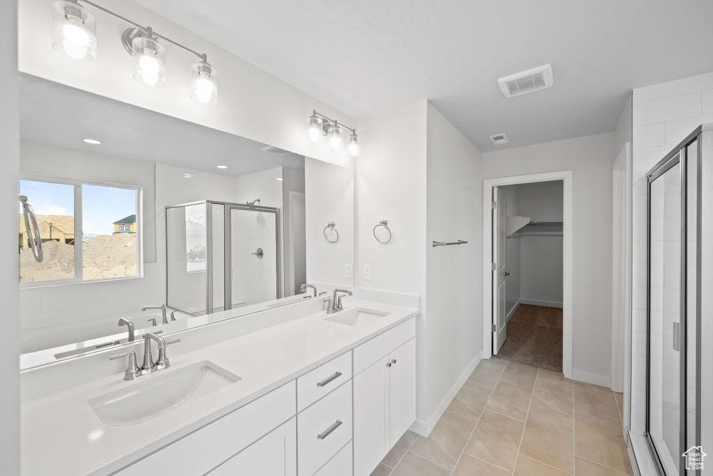 Full bathroom with a shower stall, a walk in closet, double vanity, baseboards, and tile patterned flooring
