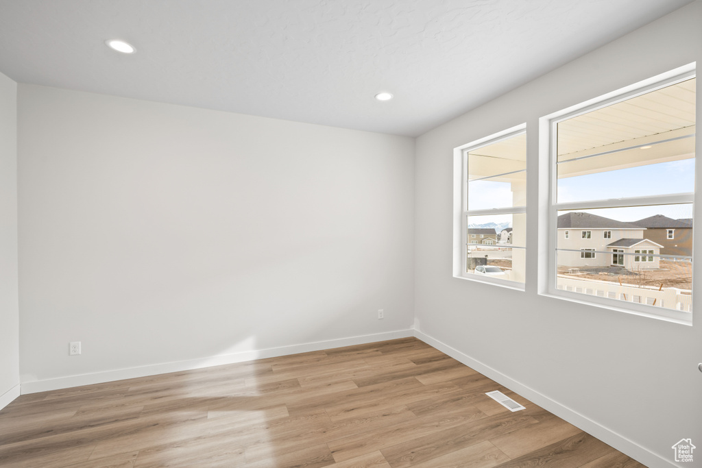 Unfurnished room with plenty of natural light, baseboards, light wood-type flooring, and recessed lighting