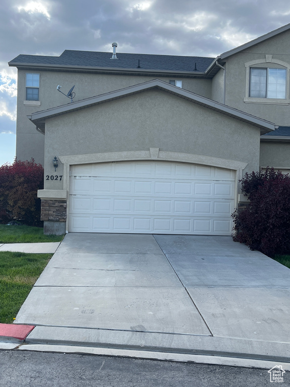 View of home\'s exterior with stucco siding, concrete driveway, and a garage