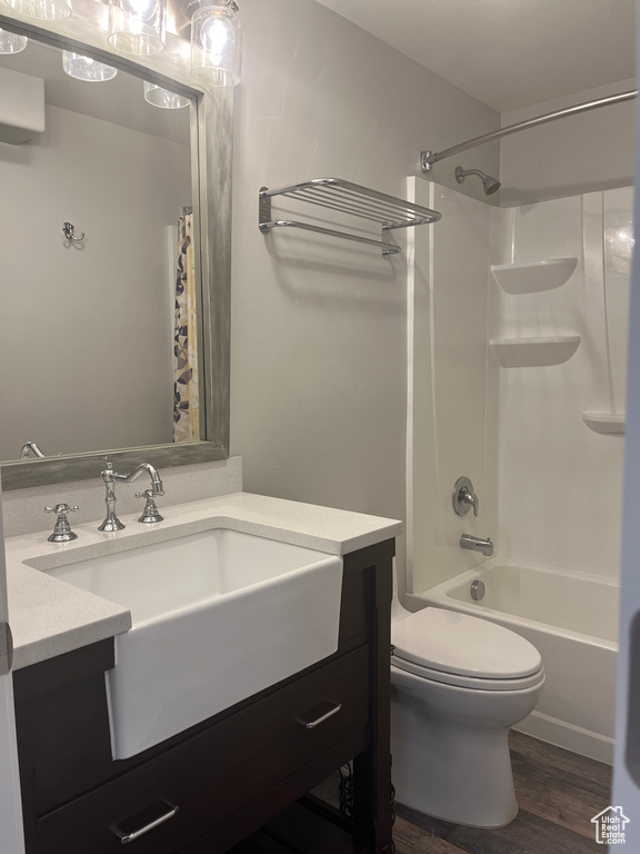 Bathroom with vanity, toilet, shower / bath combination with curtain, and wood finished floors